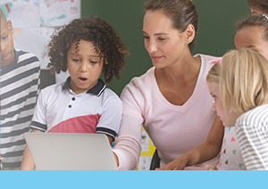 Teacher pointing at laptop as two elementary boys watched engaged and surprised