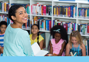 Teacher turning from her students to smile while holding a picture book