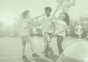 Three elementary students having fun blowing bubbles outside