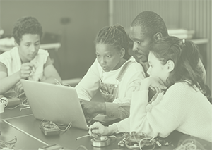 Students and teacher looking intently at a laptop screen