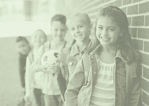 Elementary students lined up against brick school wall