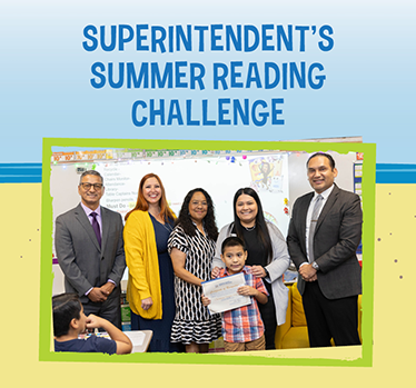 Superintendent's Summer Reading Challenge winner is a young boy holding his certificate surrounded by smiling adults