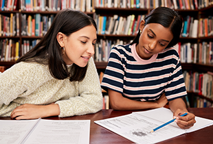 Young woman tutoring a younger woman in the library