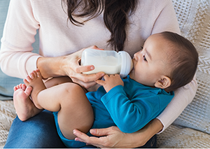 Adult feeding infant in her arms