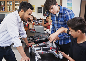 Instructor supervising two students with technical hands on activity