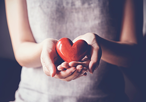 woman reaching out with red heart cupped in her hands